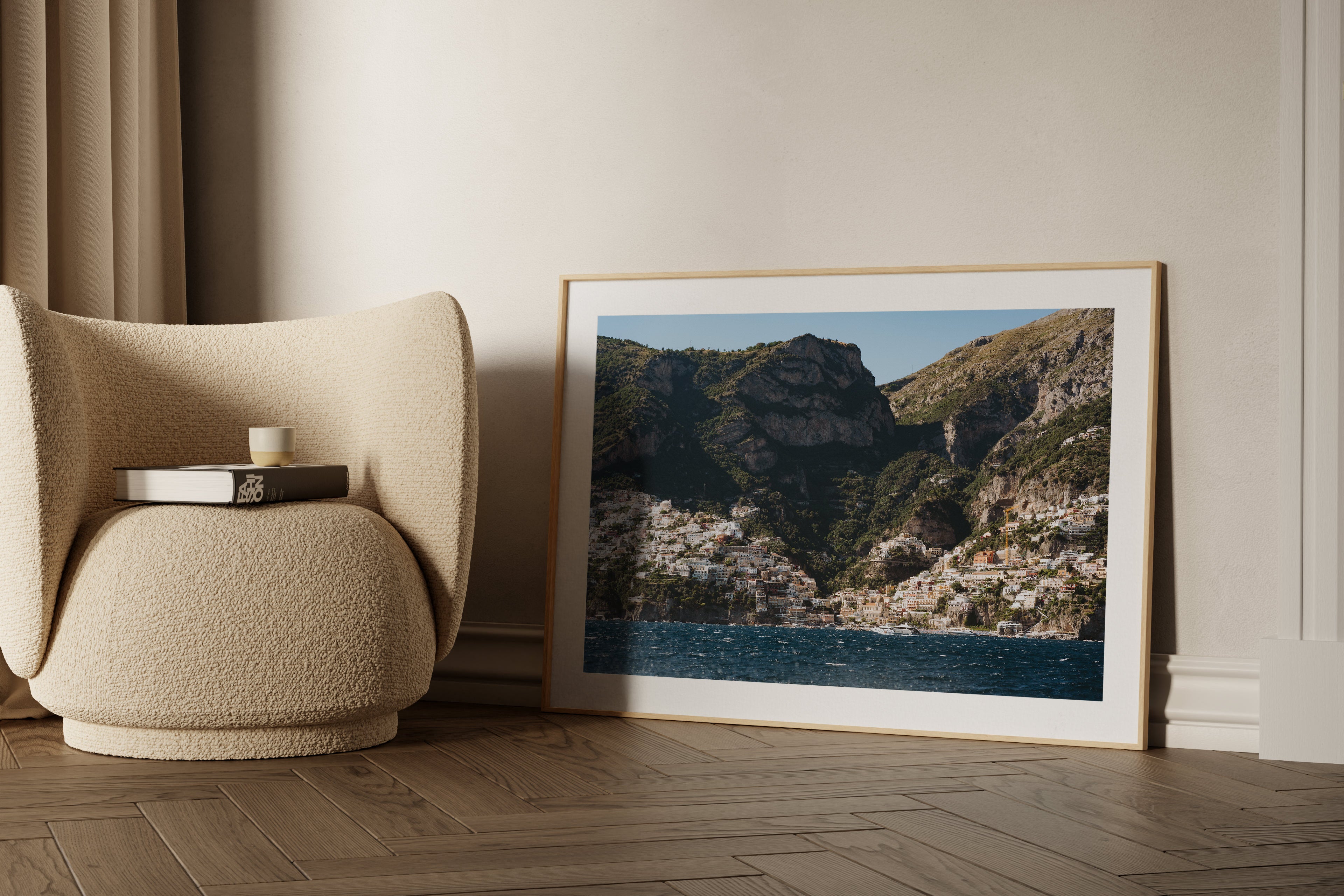 "Positano Panorama" framed fine art print on display in a minimalist home near a round armchair.